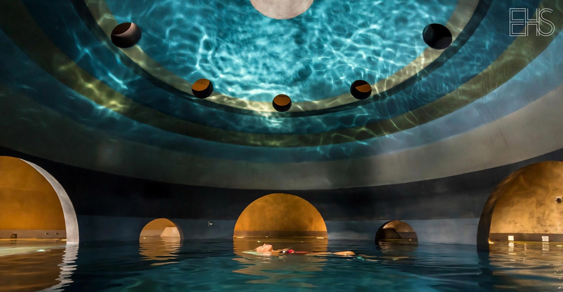 Euphoria Retreat Mystras: Byzantine-inspired domed spa building around a turquoise sphere pool at golden hour, Mount Taygetos behind