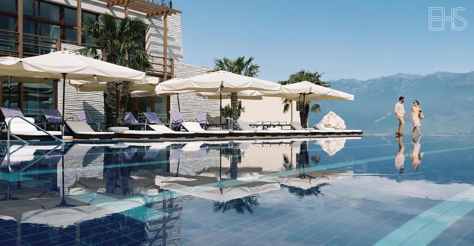 Outdoor pool deck with white umbrellas and loungers beside the resort's wood-slat architecture at Lefay Resort Lake Garda