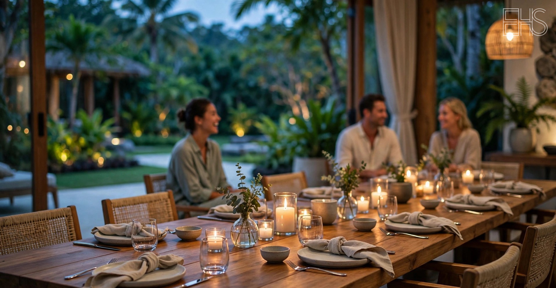 Candlelit communal dining table at a luxury wellness retreat at dusk, guests conversing quietly