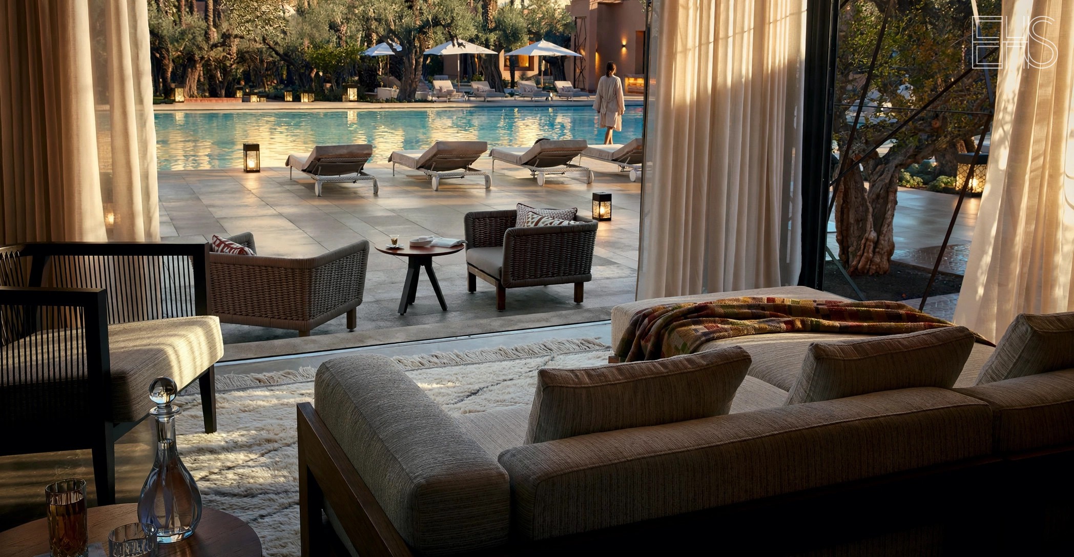 Woman in a linen robe walking beside the Le Jardin pool at Royal Mansour Marrakech at golden hour